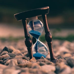 Tilted hour glass on pebbles
