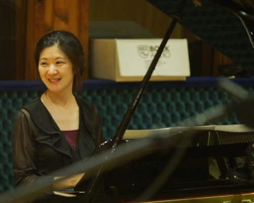 Ellen seated at a grand piano and smiling