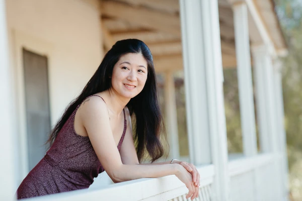 Ellen Tsai leaning on white railing and smiling.  Photo credit: Montoya Photography
