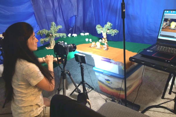 Ellen working at a stop-motion animation set with camera and laptop