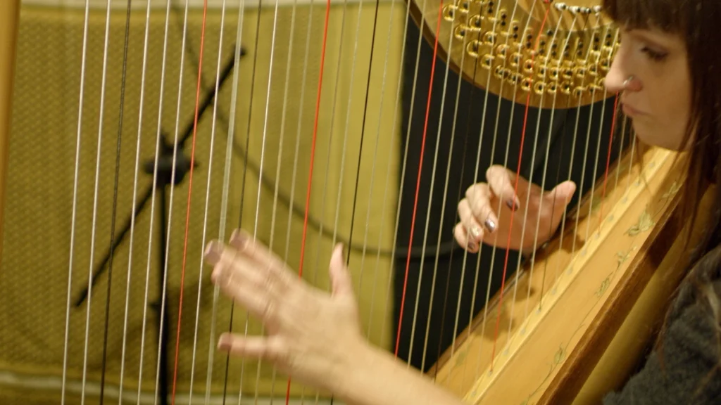 lady playing the harp in a recording studio