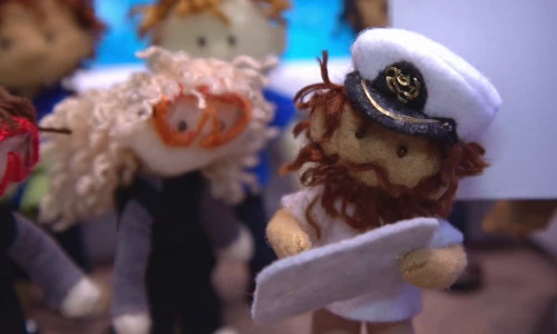 stop-motion image of a miniature ship captain doll showing something to a diver